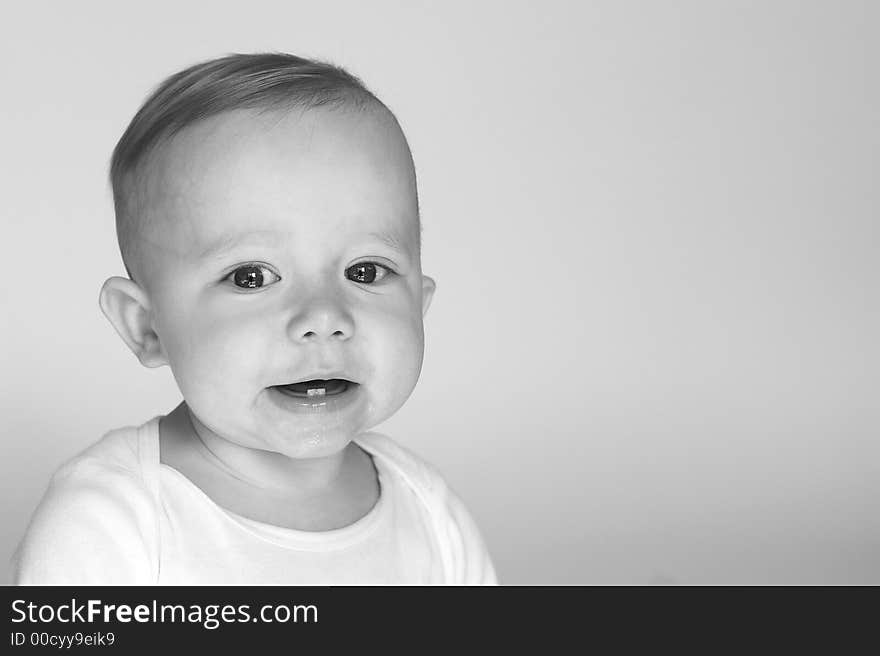 Black and white image of cute smiling baby sitting in front of a white background