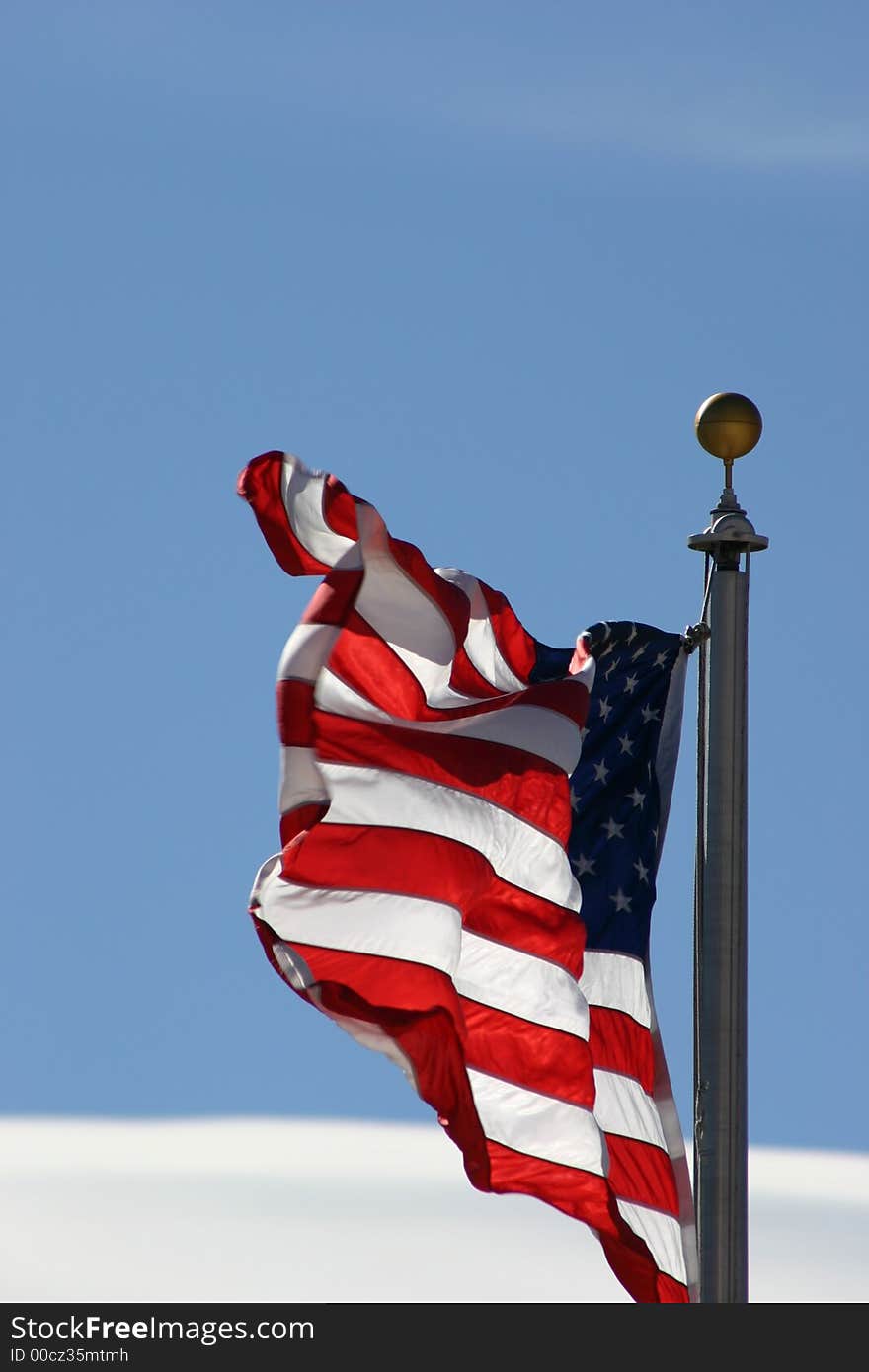 American Flag waving against a blue sky background. American Flag waving against a blue sky background