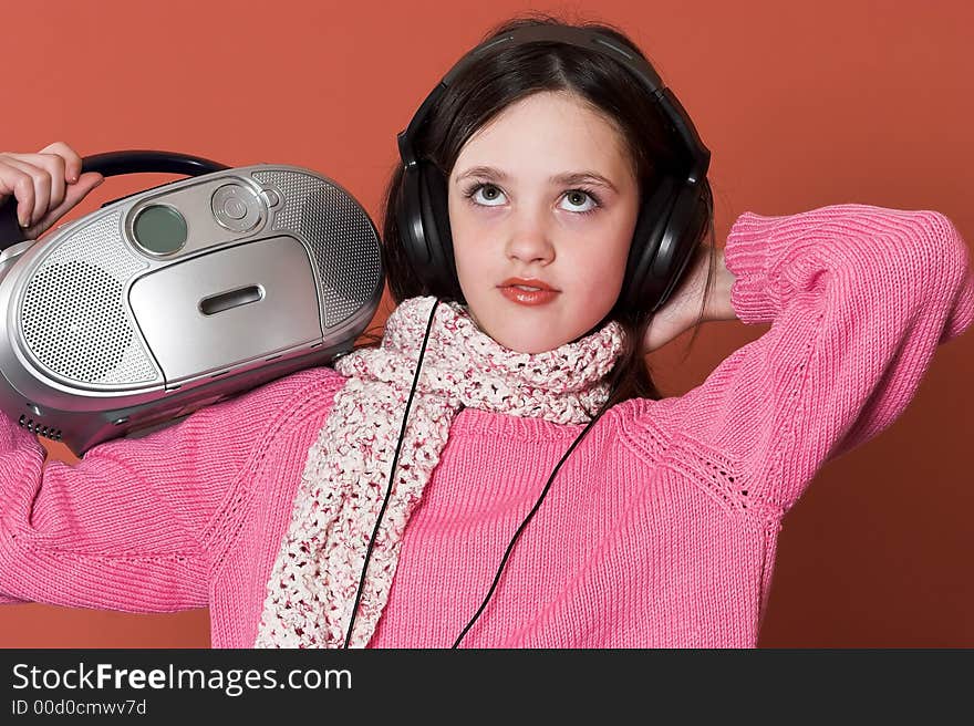 Pretty girl listening music with headphones and holding portable CD radio