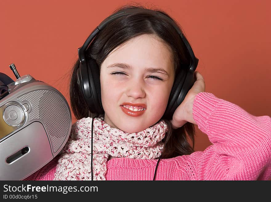 Pretty girl listening music with headphones and holding portable CD radio