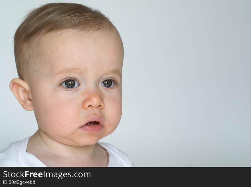 Image of beautiful 10 month old baby boy sitting in front of a white background. Image of beautiful 10 month old baby boy sitting in front of a white background