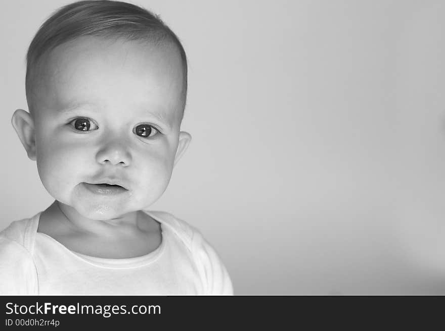 Black and white image of beautiful 10 month old baby boy sitting in front of a white background. Black and white image of beautiful 10 month old baby boy sitting in front of a white background