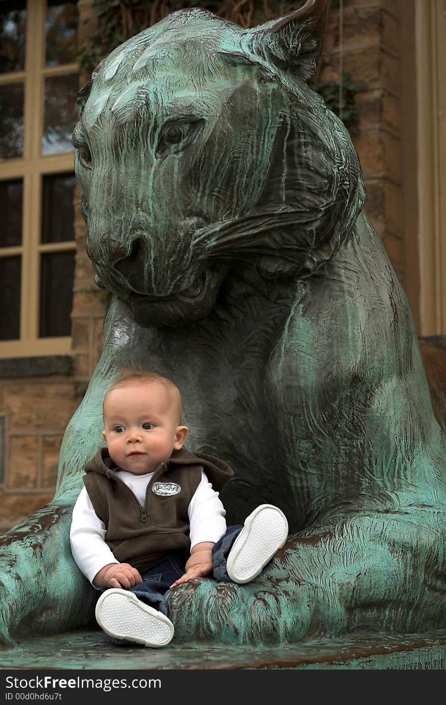 Image of cute baby sitting in front of a lion sculpture. Image of cute baby sitting in front of a lion sculpture