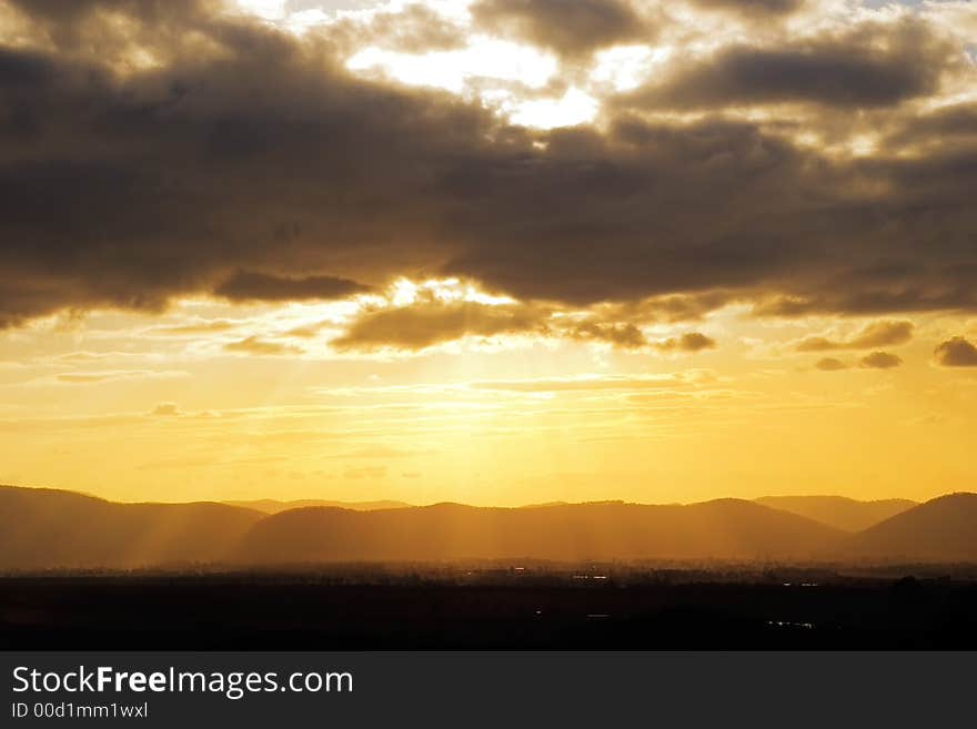 Rays from the setting sun burst out from behind clouds. Rays from the setting sun burst out from behind clouds