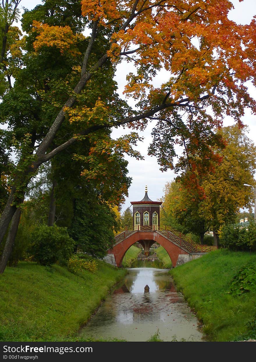 The beautiful bridge through small river, trees, autumn