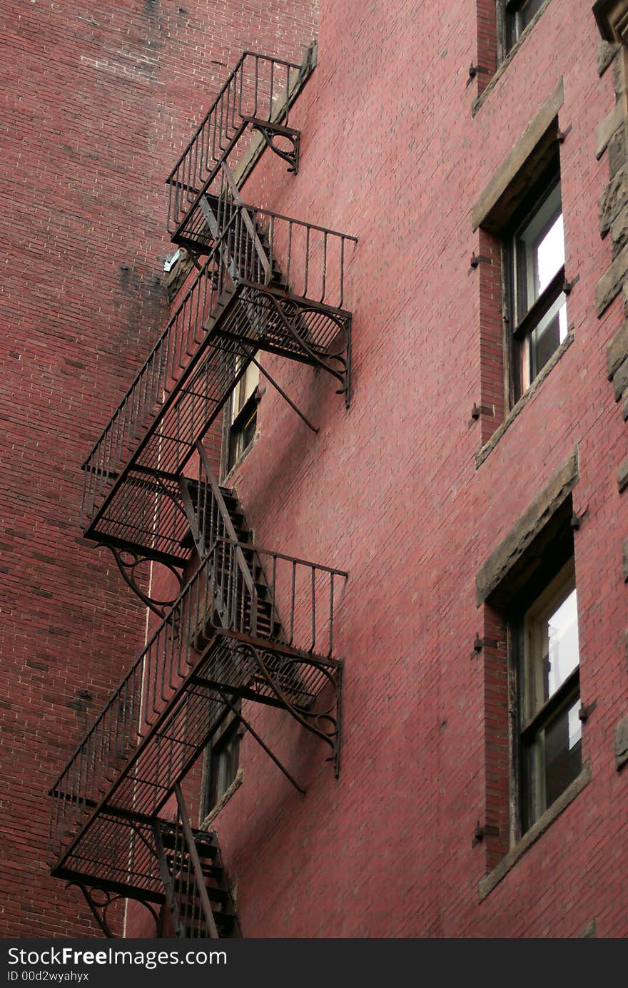 Old fire escape on back of building , showing three levels and two windows, downtown boston massachuetts on a cloudy overcast day. Old fire escape on back of building , showing three levels and two windows, downtown boston massachuetts on a cloudy overcast day