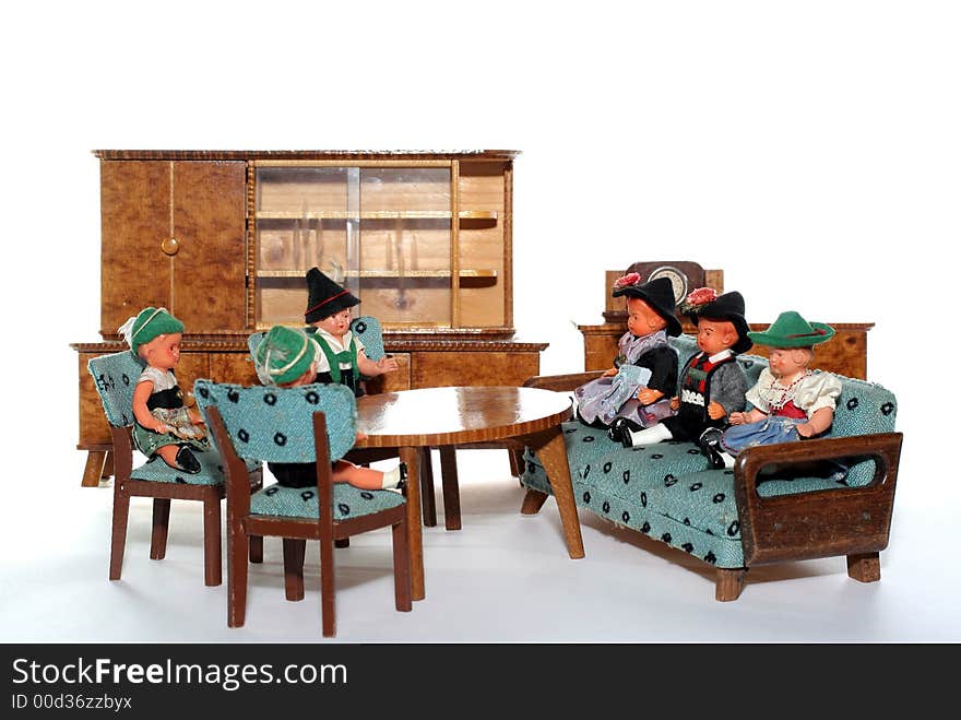 6 dolls in traditional European (I think they are Austrian but not sure) dresses sitting on chairs and couch round a table (old hand made furniture) with racks on the background. 6 dolls in traditional European (I think they are Austrian but not sure) dresses sitting on chairs and couch round a table (old hand made furniture) with racks on the background.