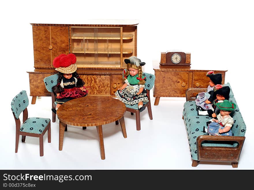 5 dolls in traditional European (I think they are Austrian but not sure) dresses sitting on chairs and couch round a table (old hand made furniture) with racks on the background. 5 dolls in traditional European (I think they are Austrian but not sure) dresses sitting on chairs and couch round a table (old hand made furniture) with racks on the background.