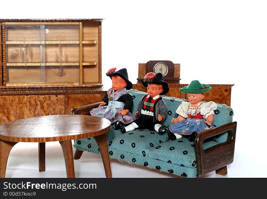 3 dolls in traditional European (I think they are Austrian but not sure) dresses sitting on a couch infront of a table (old hand made furniture) with racks on the background. 3 dolls in traditional European (I think they are Austrian but not sure) dresses sitting on a couch infront of a table (old hand made furniture) with racks on the background.