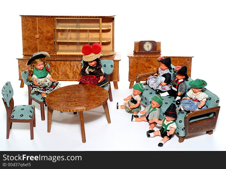 8 dolls in traditional European (I think they are Austrian but not sure) dresses sitting on chairs and couch round a table (old hand made furniture) with racks on the background. 8 dolls in traditional European (I think they are Austrian but not sure) dresses sitting on chairs and couch round a table (old hand made furniture) with racks on the background.