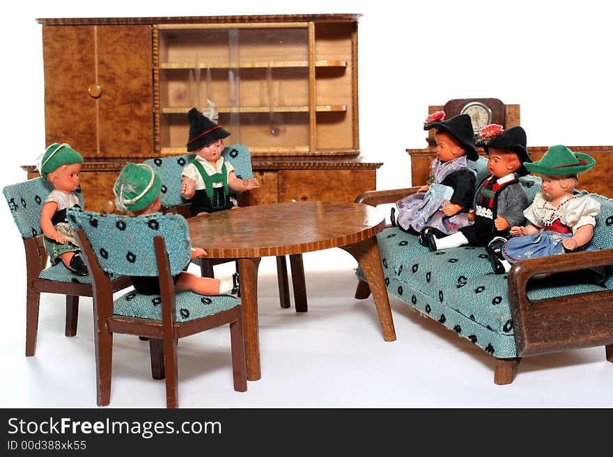 6 dolls in traditional European (I think they are Austrian but not sure) dresses sitting on chairs and couch round a table (old hand made furniture) with racks on the background. 6 dolls in traditional European (I think they are Austrian but not sure) dresses sitting on chairs and couch round a table (old hand made furniture) with racks on the background.