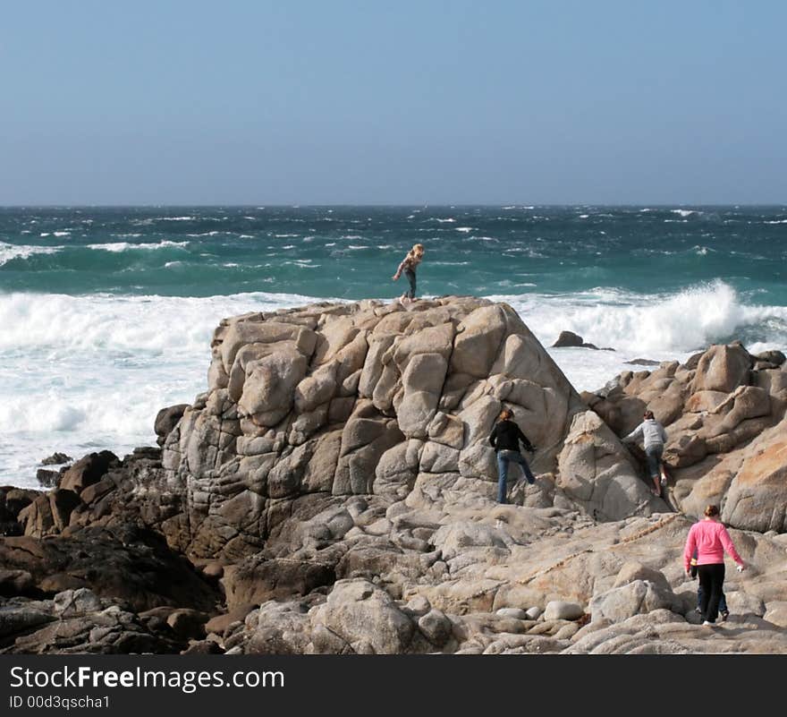 Waves crashing into rocks on Monterey Bay with people standing on the rocks