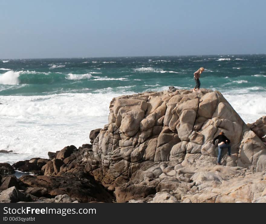 Waves crashing into rocks on Monterey Bay with people standing on the rocks