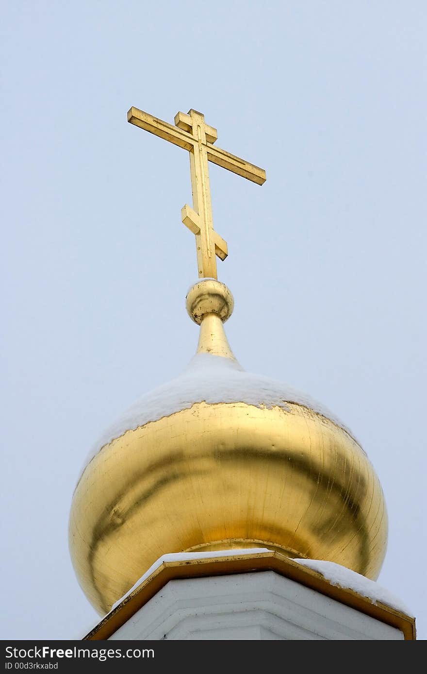 Gold dome of church close up, powdered by a snow, on a background of the monophonic blue sky