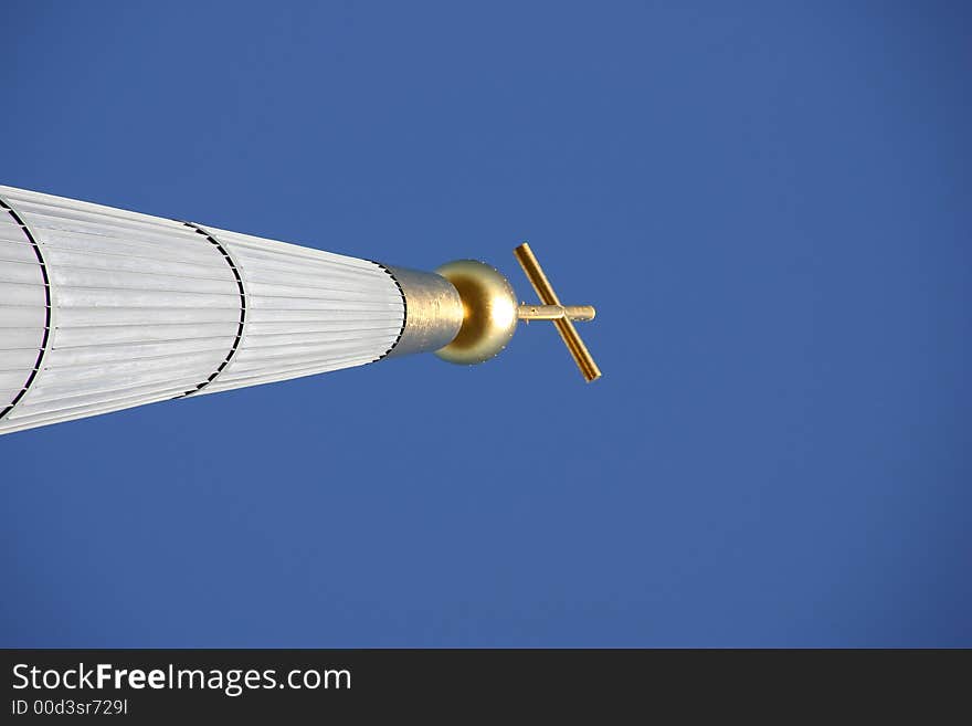 Golden cross on a modern chruch tower in front of a blue sky. Golden cross on a modern chruch tower in front of a blue sky