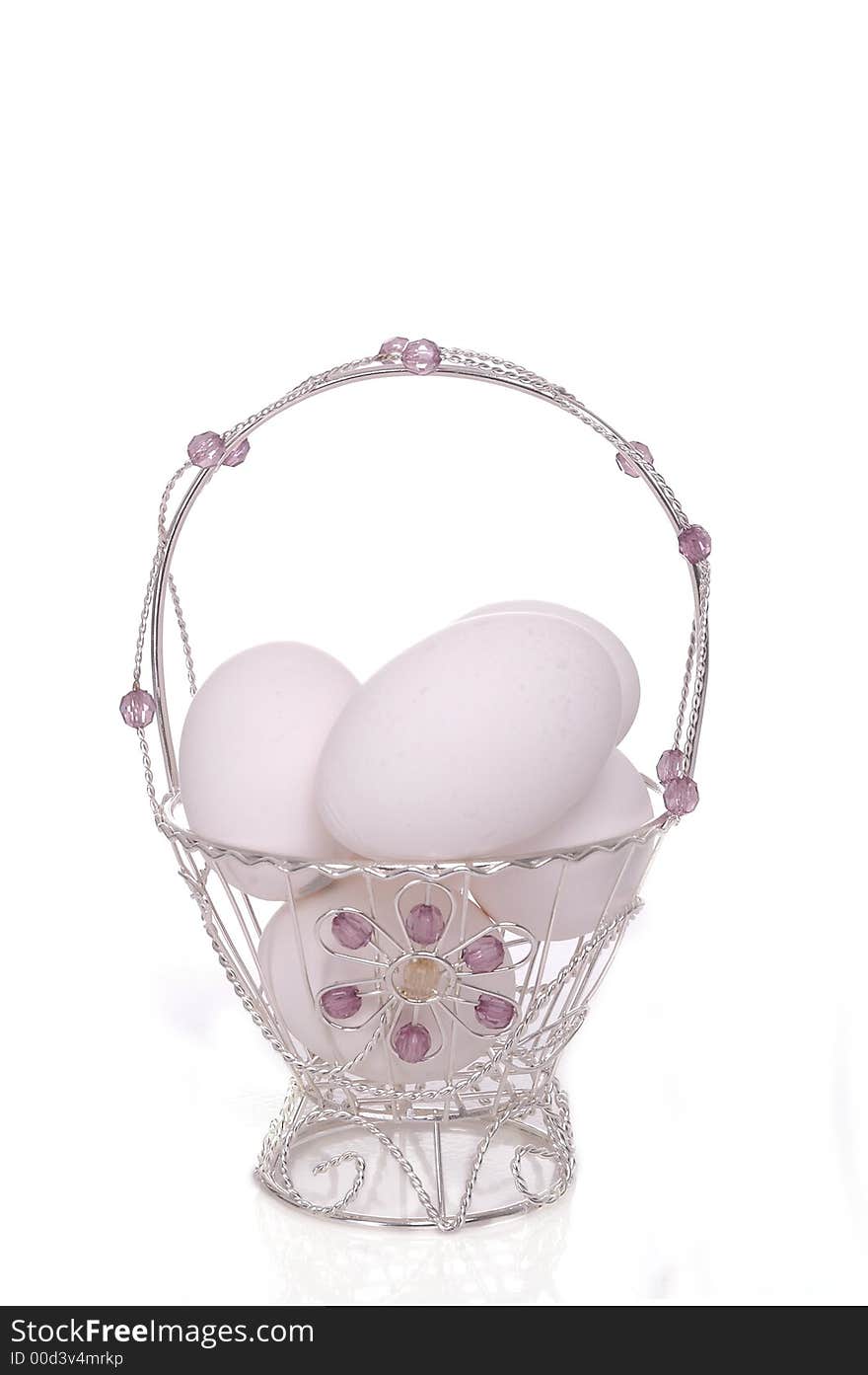 A small, dainty silver Easter basket filled with eggs. White background. A small, dainty silver Easter basket filled with eggs. White background.