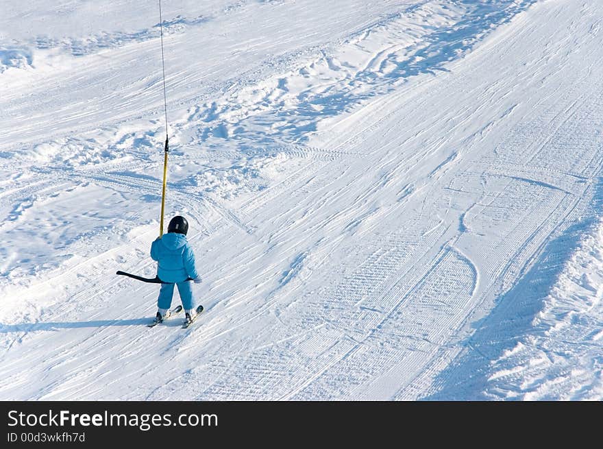 Young downhill skier going up with elevator