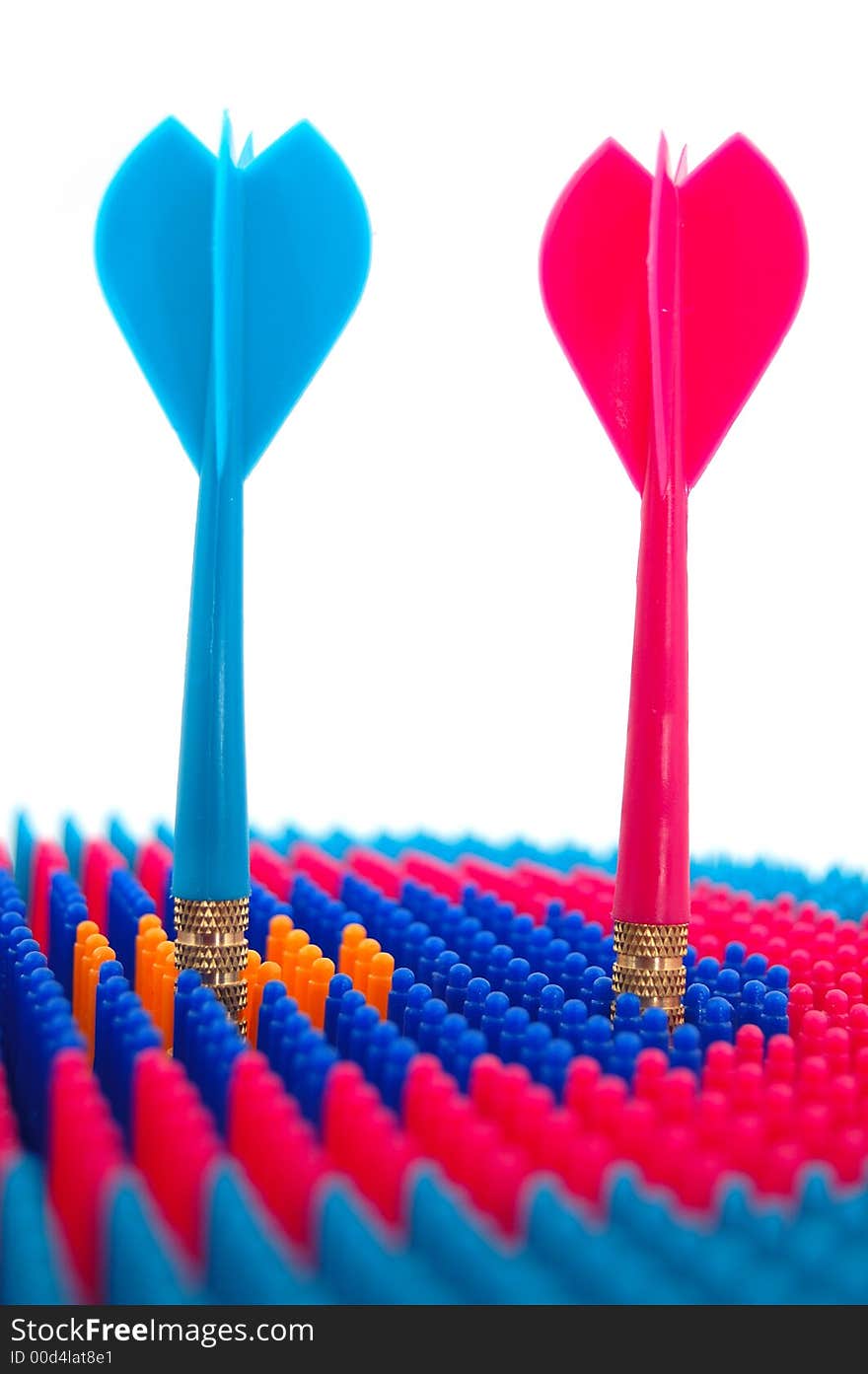 Isolated photo of red and blue toy darts pinned to the target, representing the concept of competition. Isolated photo of red and blue toy darts pinned to the target, representing the concept of competition.