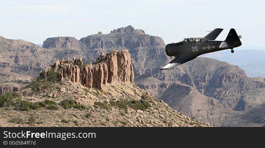 An old military prop plane flies low over a desert landscape in the superstition mountains of Arizona. Taken from on top of the flatiron. An old military prop plane flies low over a desert landscape in the superstition mountains of Arizona. Taken from on top of the flatiron.