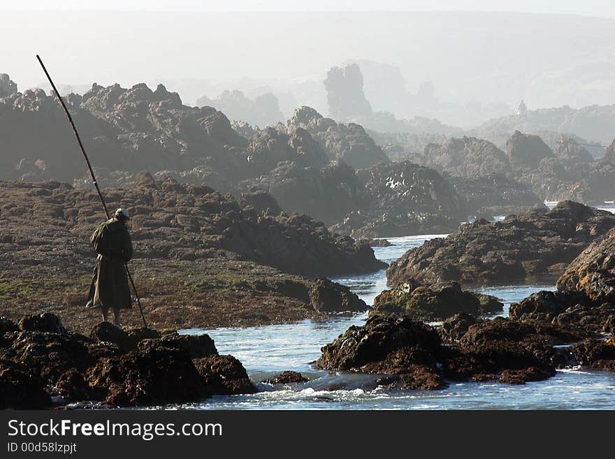 In an ocean wave a fisherman catches fishes. In an ocean wave a fisherman catches fishes