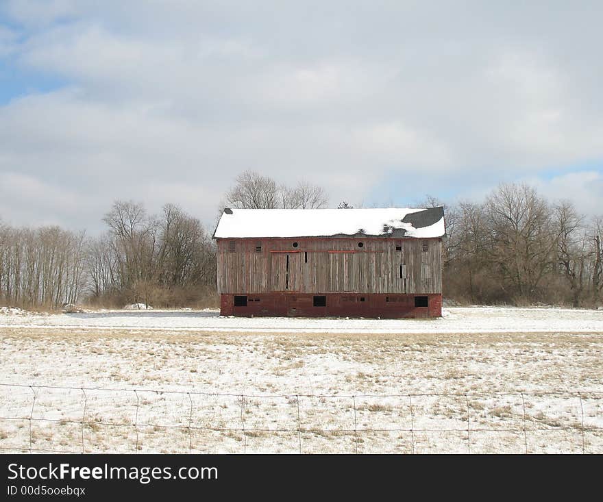 Big wooden barn with snowy roof in snow field