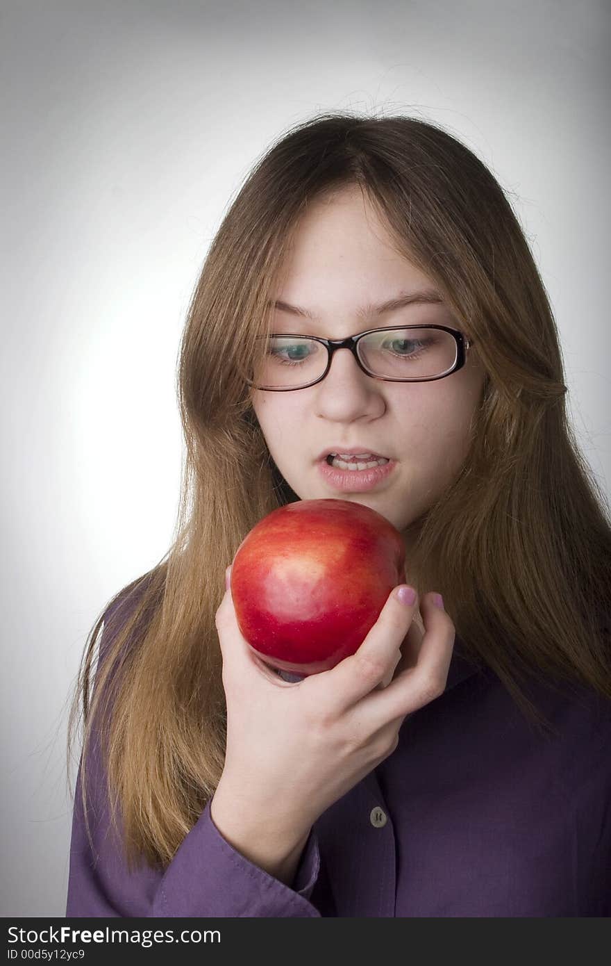 Young smiling girl eating the big red apple. Young smiling girl eating the big red apple