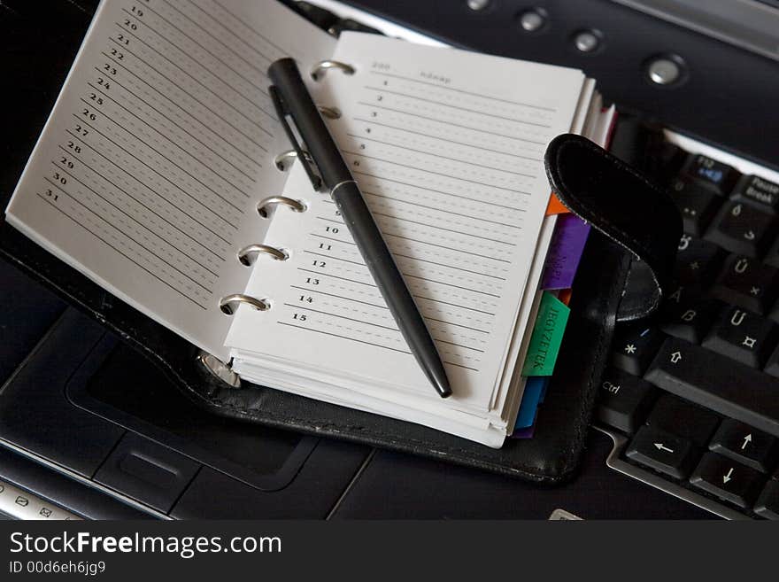 Agenda and pen on a black laptop keyboard. Agenda and pen on a black laptop keyboard