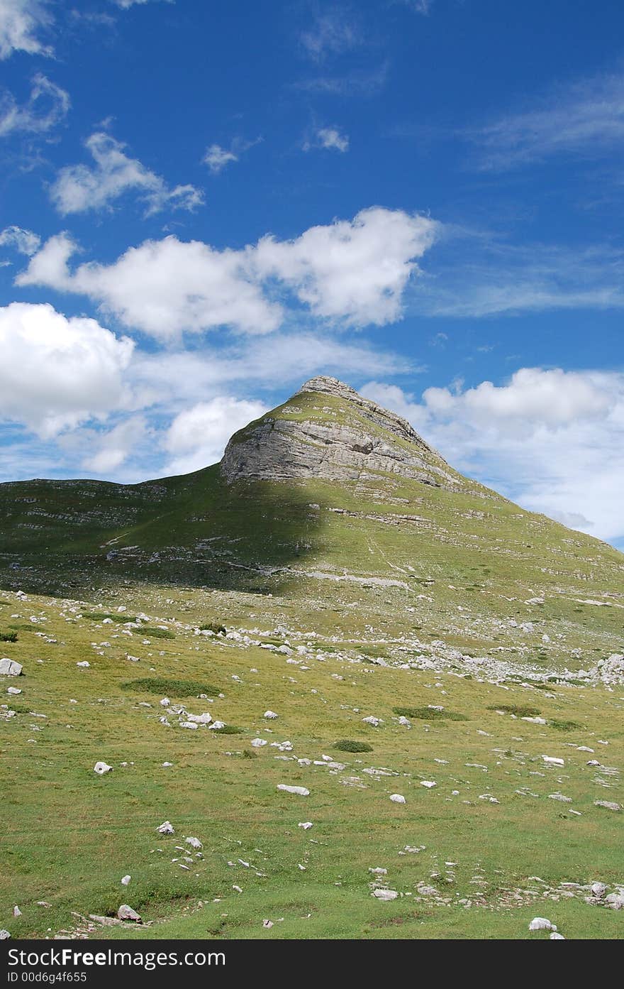 Peak, blue sky, green grass on mountine Durmitor