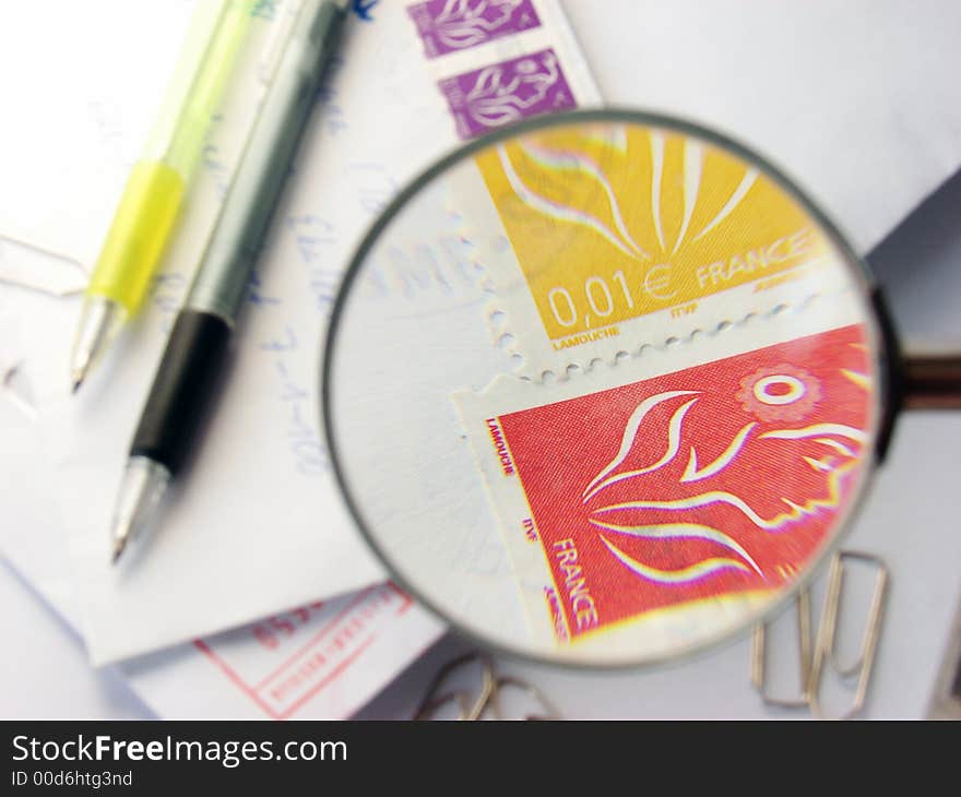 Two pens under an stamped envelop close-up with the magnifying g