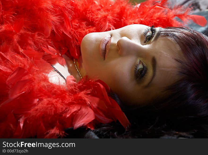 Woman inside plumes. She is lying on bed and looking at camera.