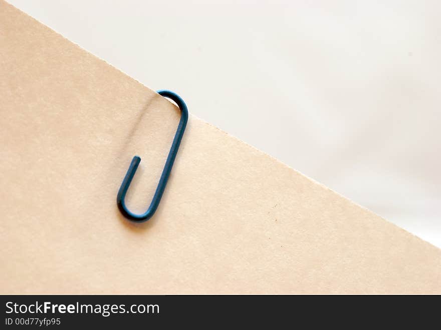 A blue paper clip on a piece of paper. A blue paper clip on a piece of paper