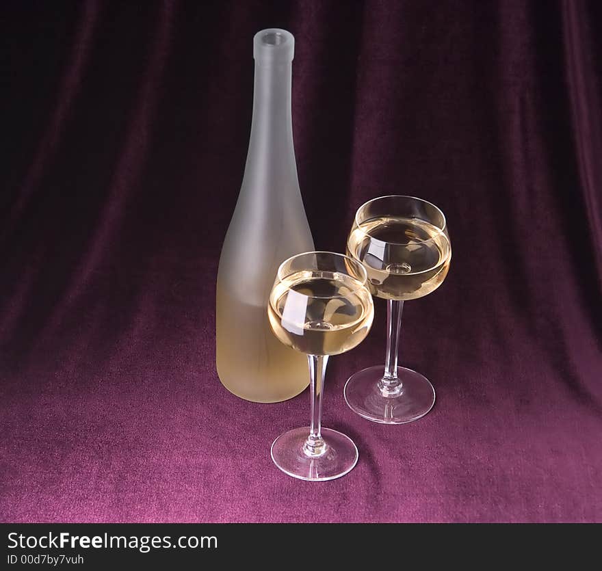 White wine in two glasses and bottle on a claret background