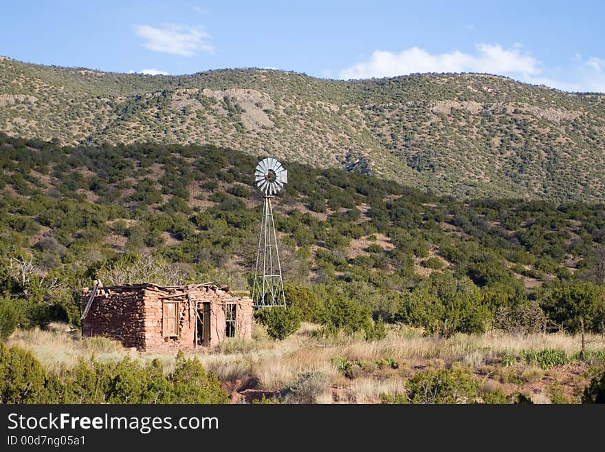 An old homestead and windmill in the foothills of a mountain range. An old homestead and windmill in the foothills of a mountain range