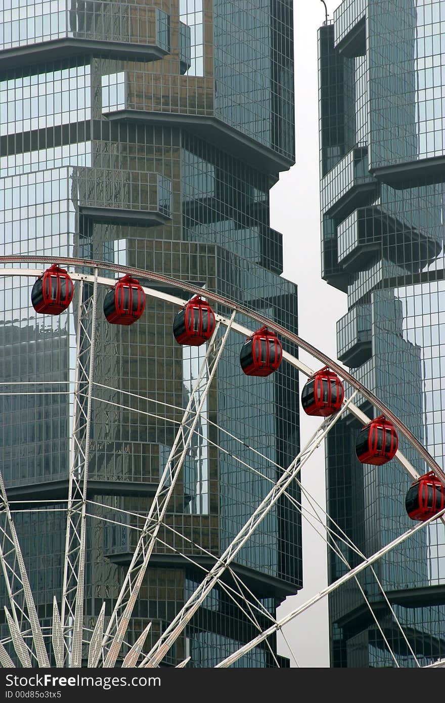 Giant observation wheel, mirror glass skyscraper on the background