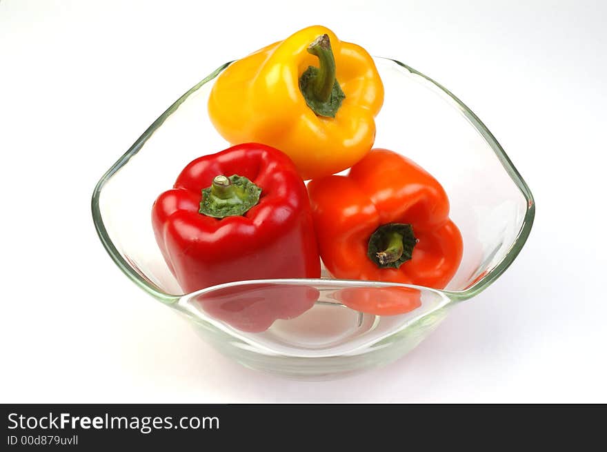 Yellow, orange, and red bell peppers in a glass bowl on a white background. Yellow, orange, and red bell peppers in a glass bowl on a white background