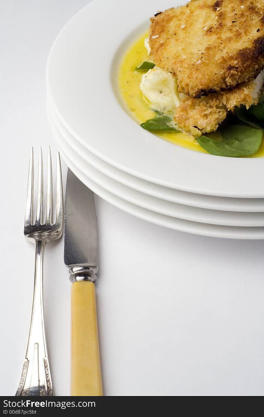 Chicken schnitzel, baked with potato mash, baby spinach and beure blanc sauce. Portrait view with antique knife and fork. Chicken schnitzel, baked with potato mash, baby spinach and beure blanc sauce. Portrait view with antique knife and fork.