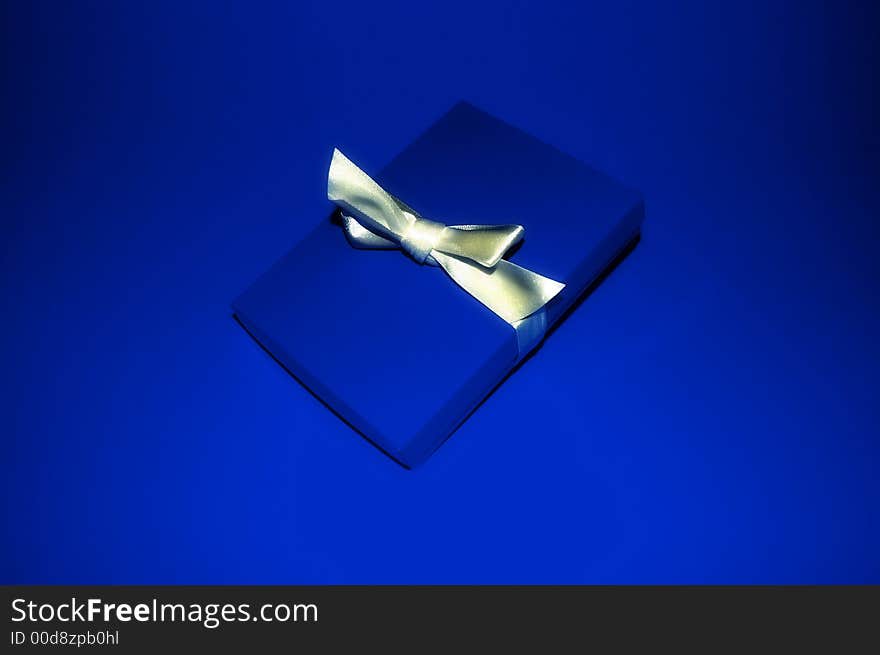 A blue gift box with a silver ribbon. A blue gift box with a silver ribbon.