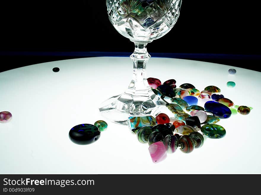 A collection of multi colored beads and glass goblet. A collection of multi colored beads and glass goblet