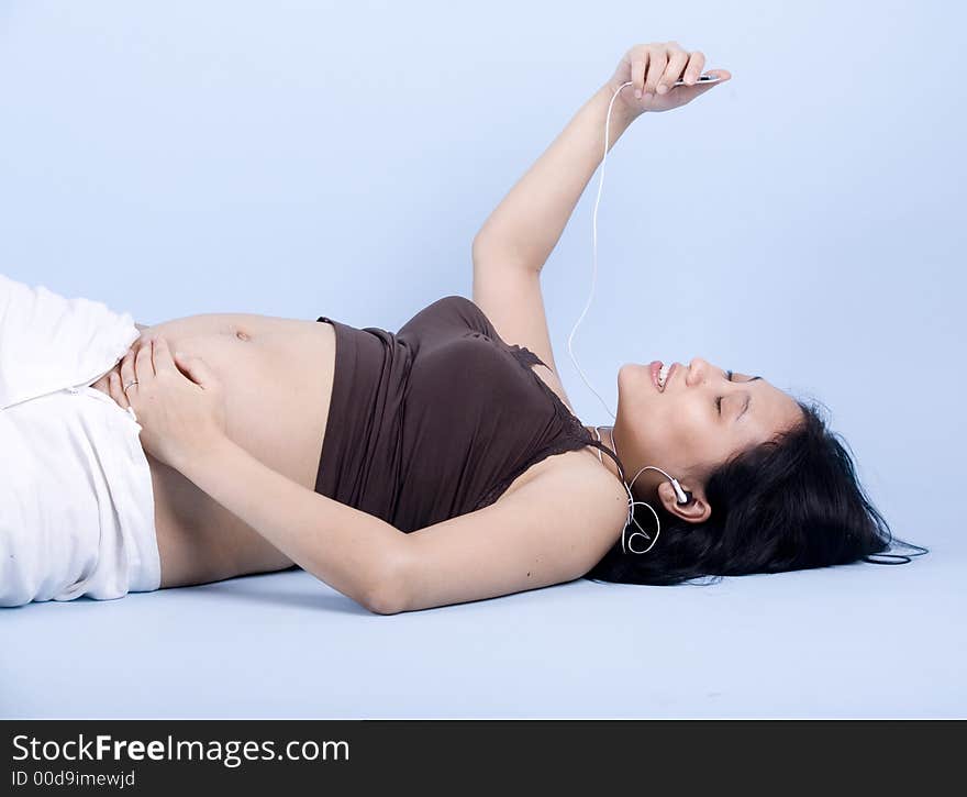 Isolated Pregnant woman listening to classical music over blue background. Isolated Pregnant woman listening to classical music over blue background