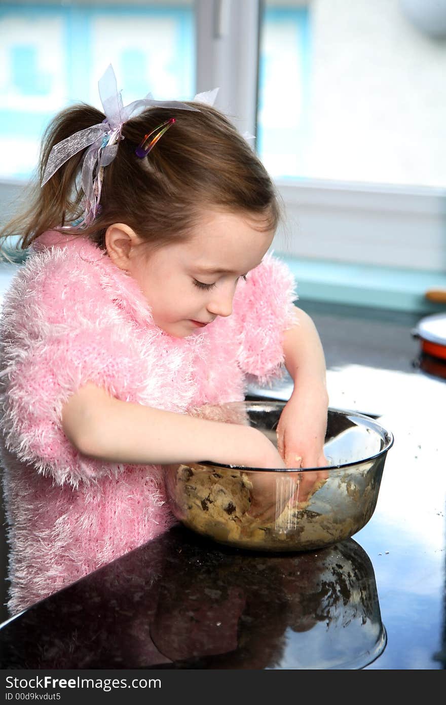 Young girl mixing food ingredients in a bowl with her hands. Young girl mixing food ingredients in a bowl with her hands