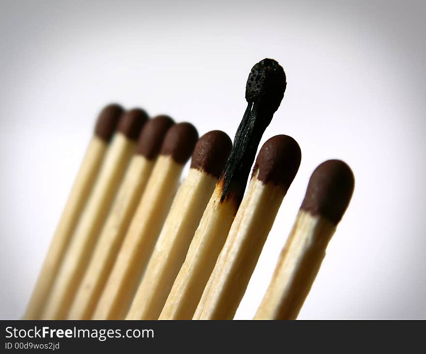 Close-up photo of several matches in a row with one burnt