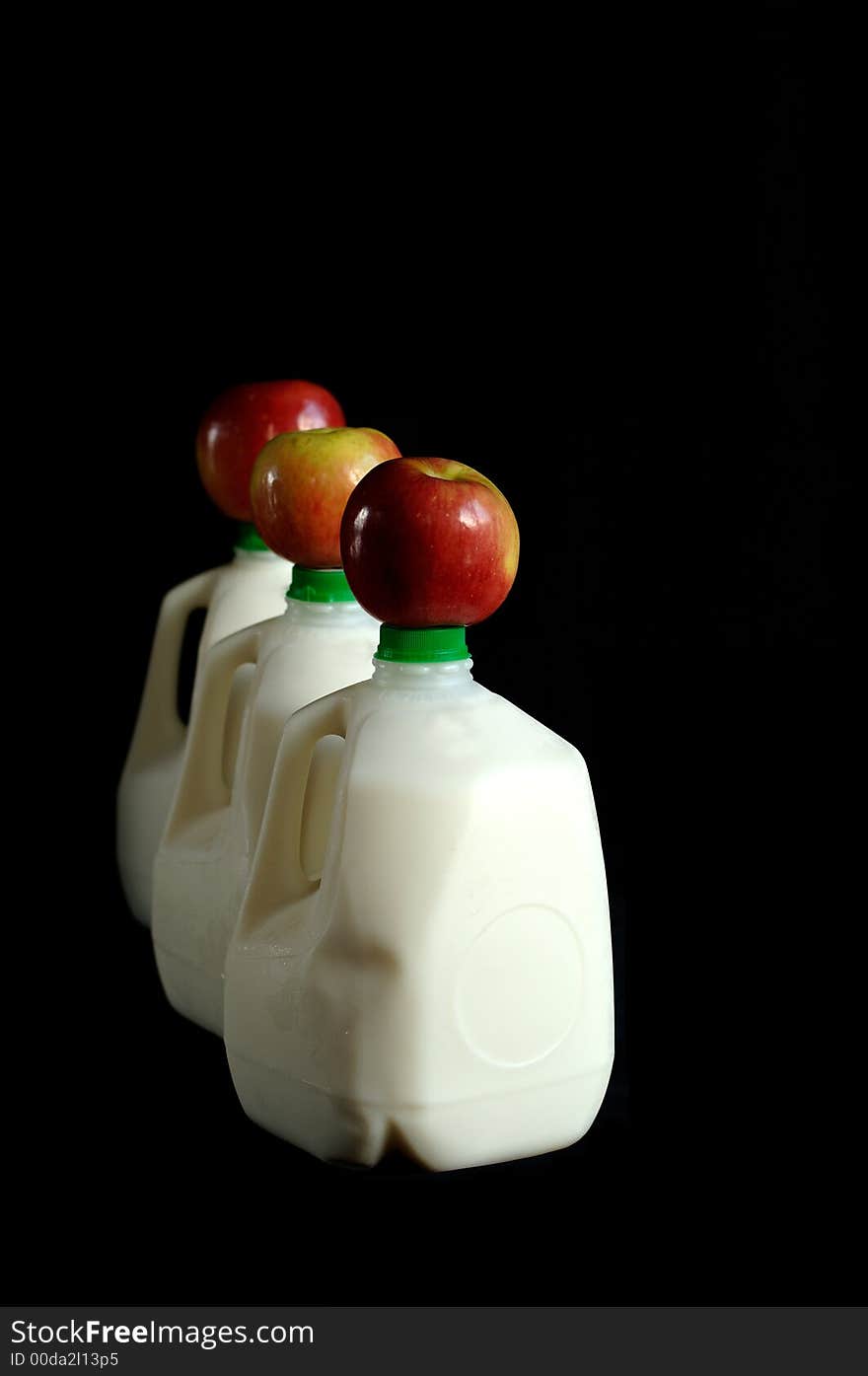 Three apples resting atop three cartons of milk. Three apples resting atop three cartons of milk