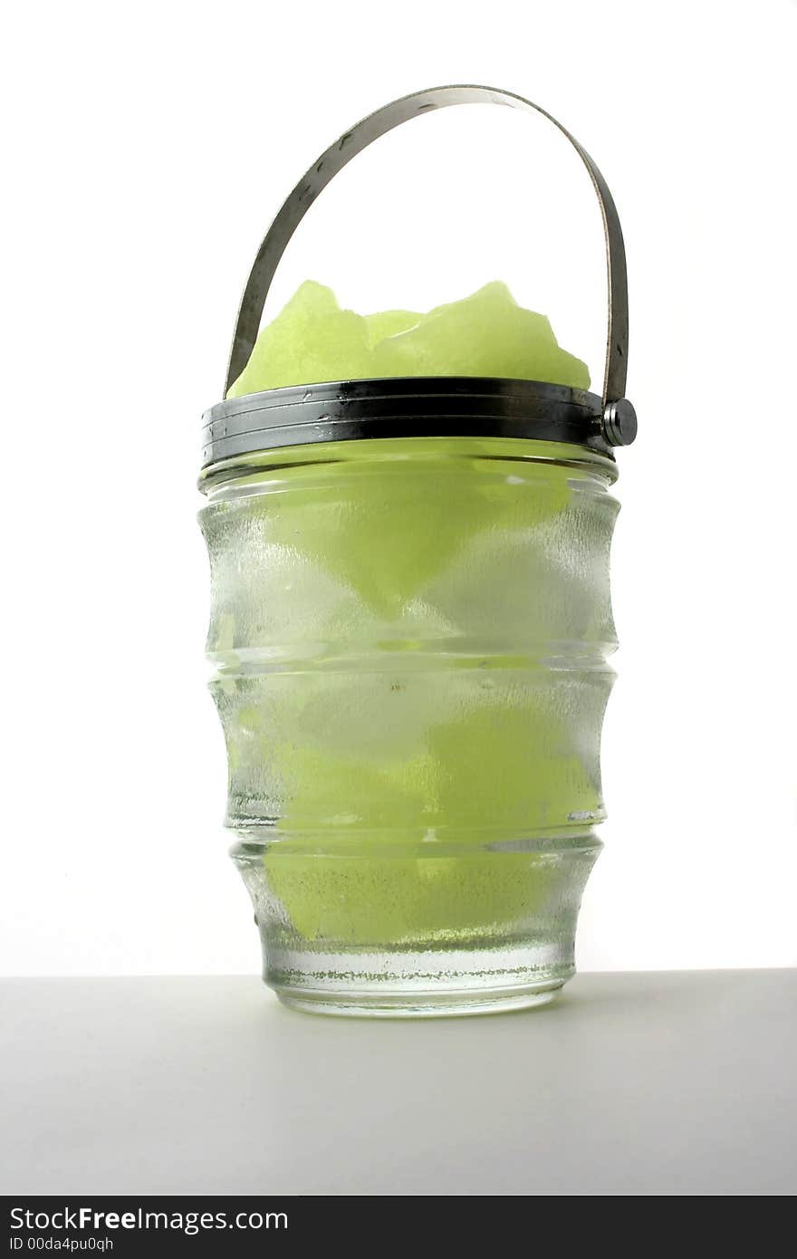 Yellow and white ice cubes put in a glass jug with metal handle