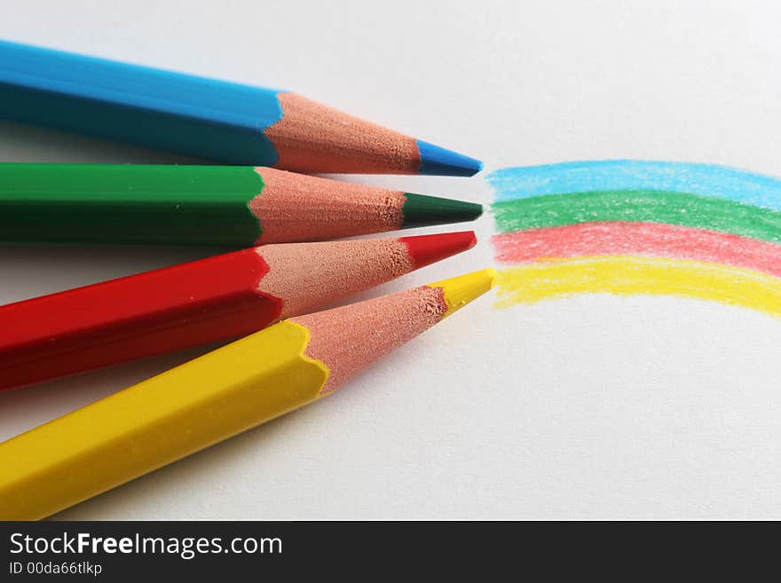 A macro shot of the front end of a group of colored pencils, isolated on white, with the colors of the rainbow drawn on the paper in front. A macro shot of the front end of a group of colored pencils, isolated on white, with the colors of the rainbow drawn on the paper in front