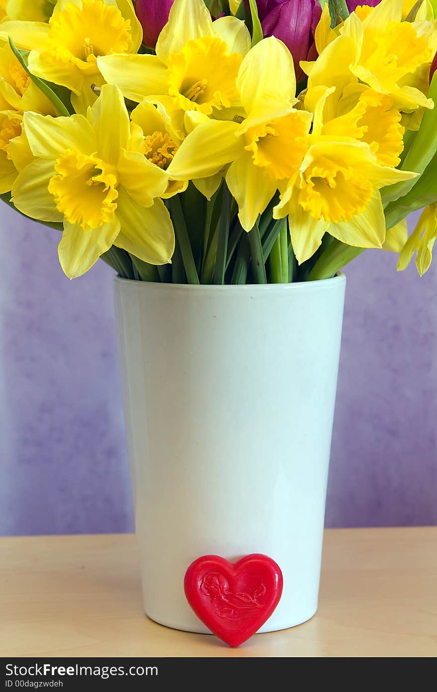 Brightly coloured spring flowers on a vase with a red heart. Brightly coloured spring flowers on a vase with a red heart