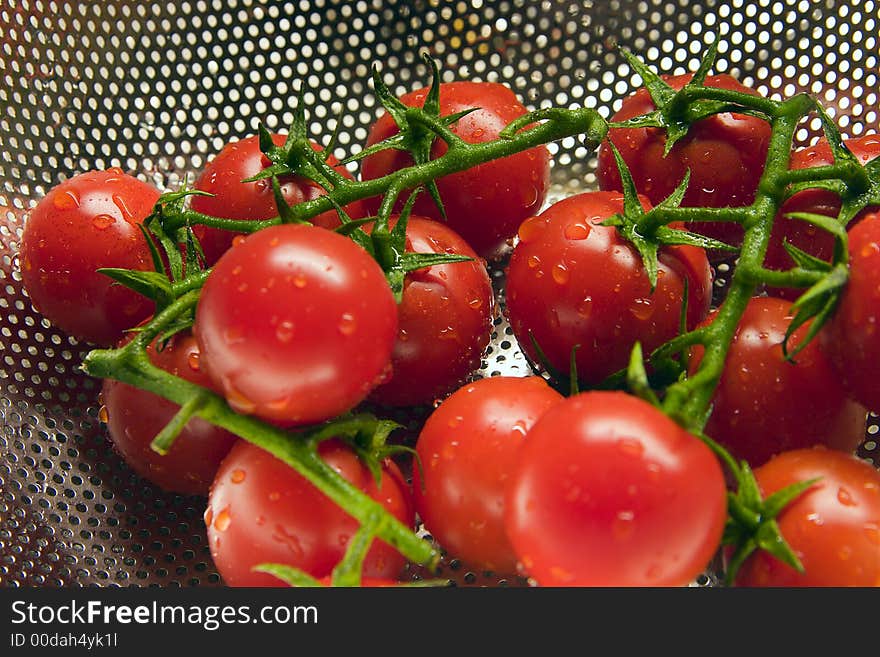 Freshly washed tomatoes in a stainless steel colander