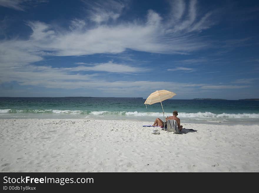 Couple sitting on a tropical beach under an umbrella. Couple sitting on a tropical beach under an umbrella