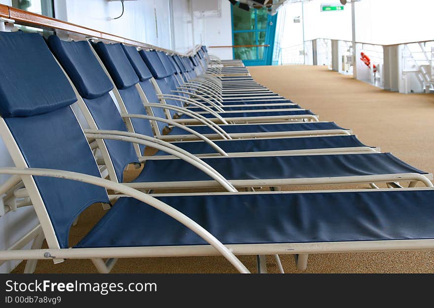 Blue lounge chairs lined up on deck of a ship. Blue lounge chairs lined up on deck of a ship