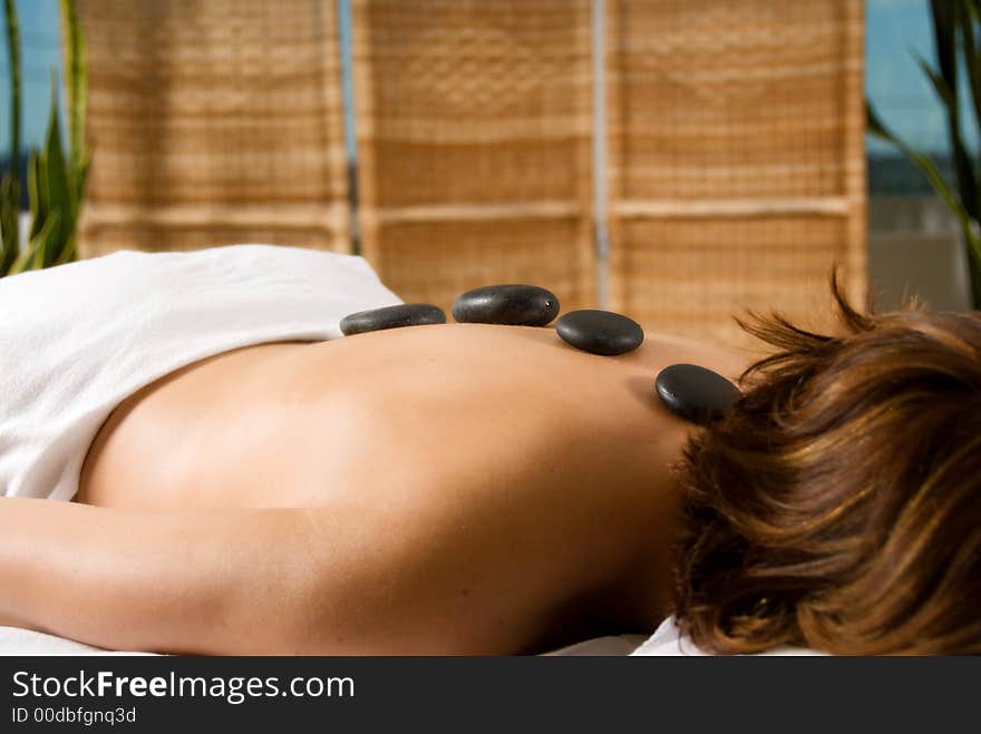 Woman in a day spa with hot stones on her back. Woman in a day spa with hot stones on her back