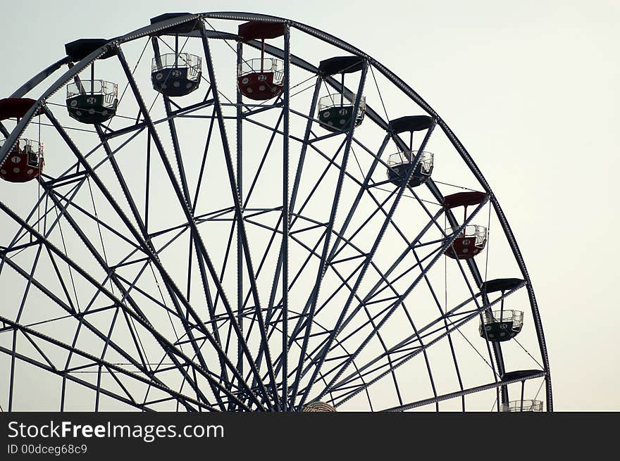 Ferris wheel silhouette against a bright sky